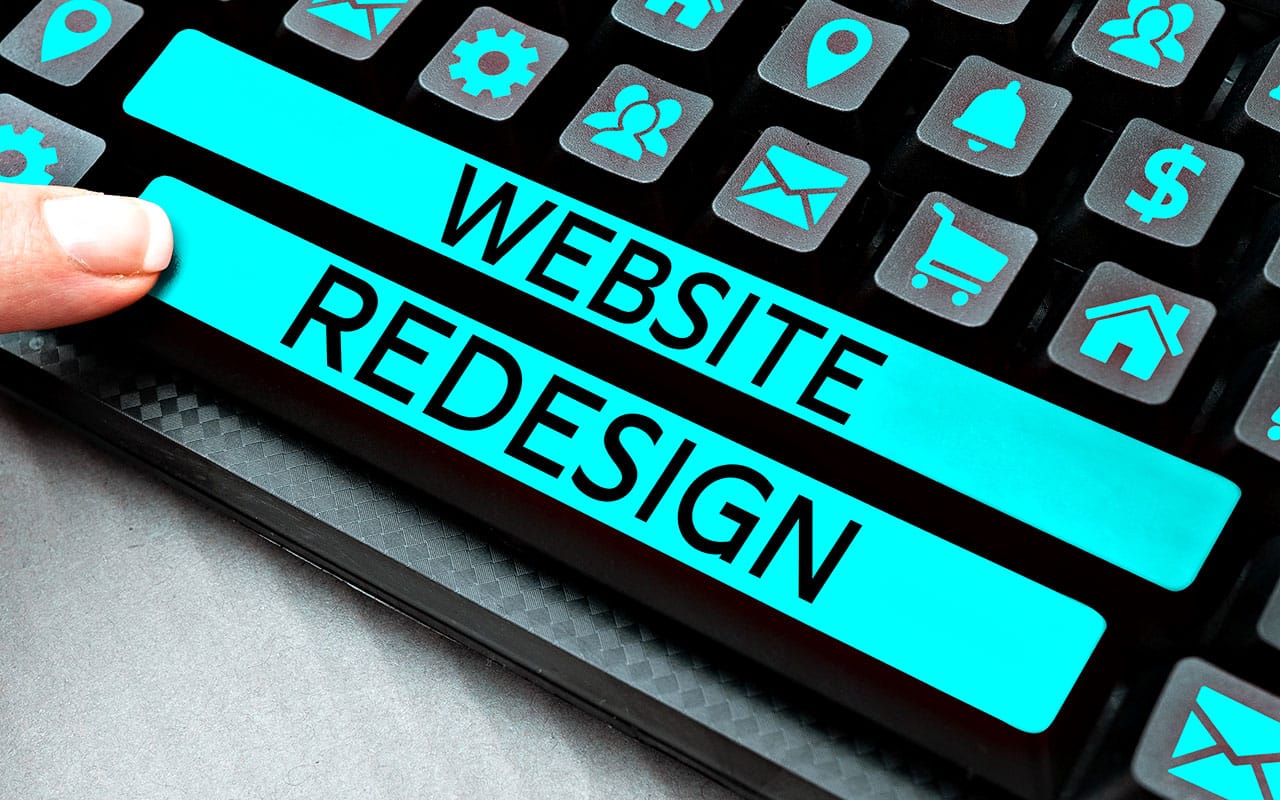 Finger pressing website redesign button on a computer keyboard