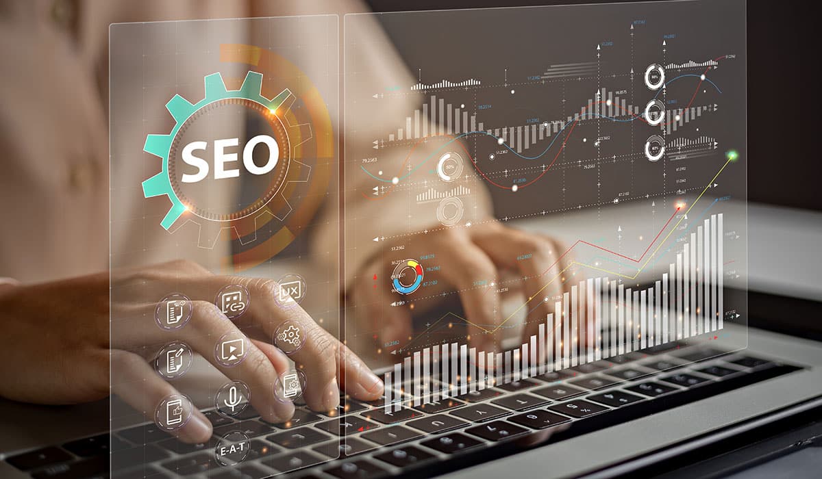Hands typing on laptop with SEO and analytic graphs overlay