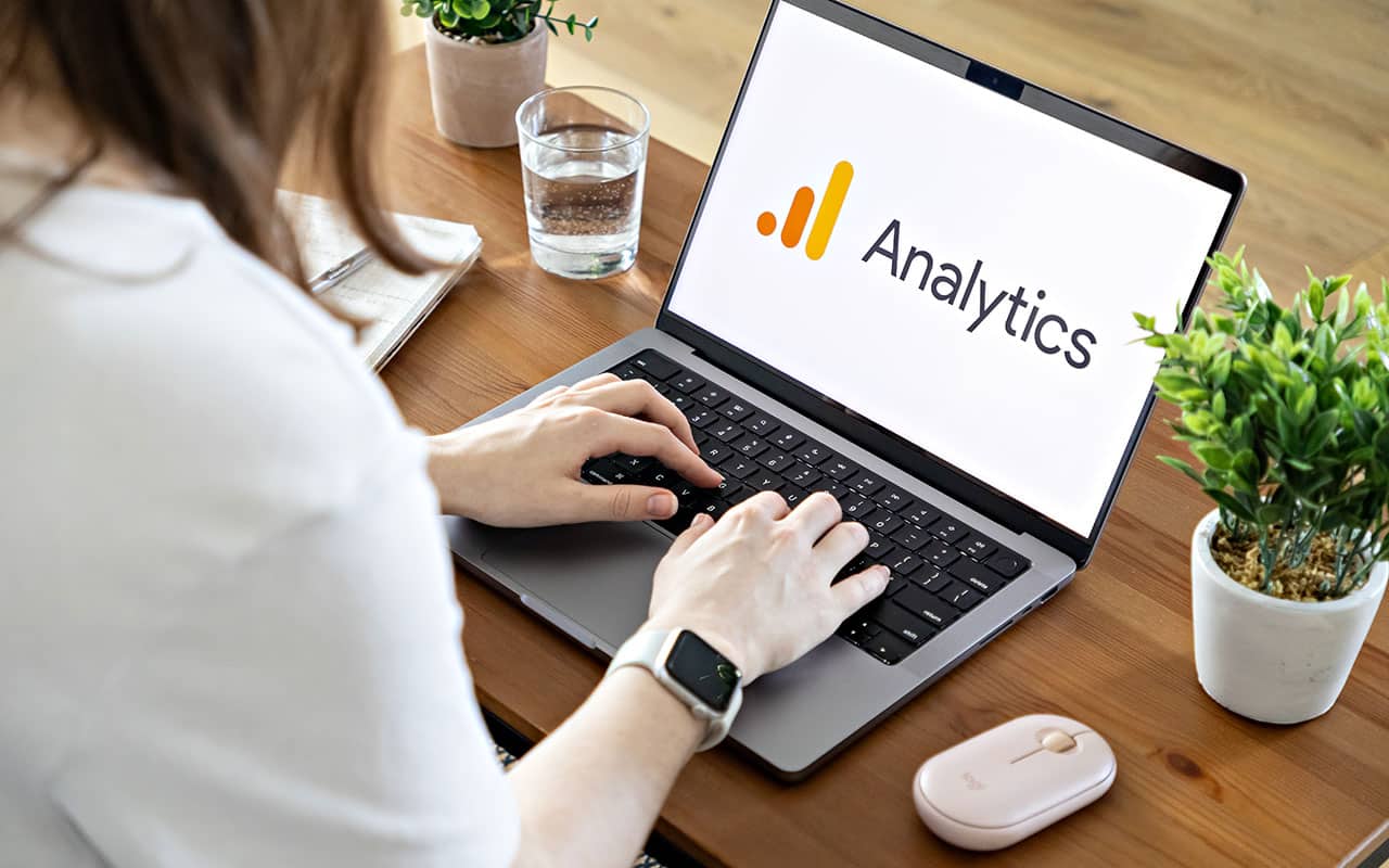 Person using Google Analytics on a laptop at a wooden desk