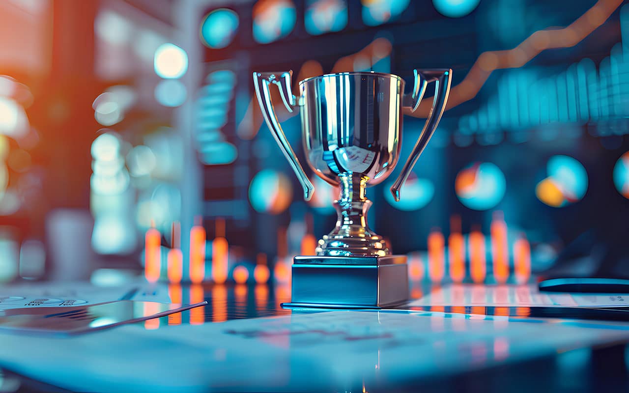 Silver trophy on office desk with financial charts and graphs