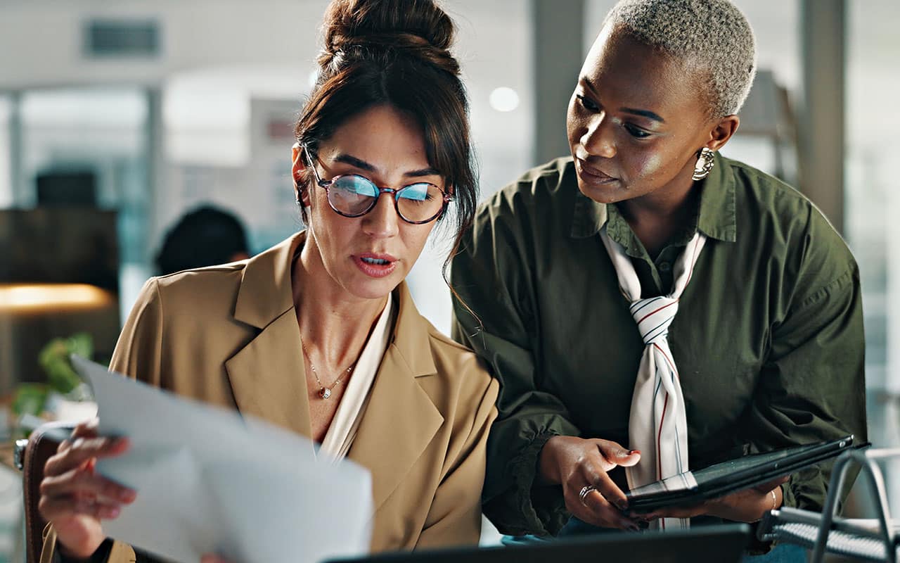 Two businesswomen reviewing documents in a modern office environment